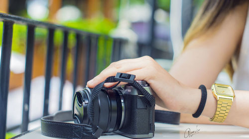 Close-up of woman photographing camera on table