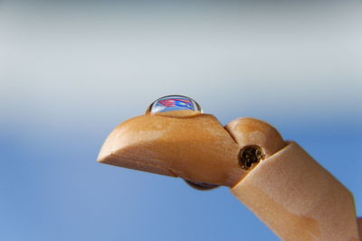 Close-up of hand holding ring against blue sky