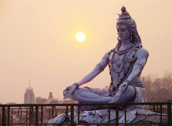 Shiva statue against sky during sunrise