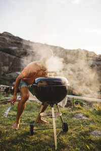 Man on barbecue grill against sky