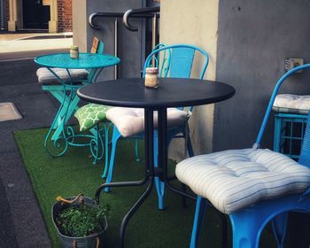 Empty chairs and table against wall in yard