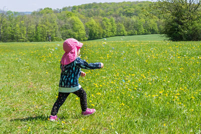 Full length of woman with pink flowers on field