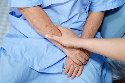 Midsection of man with hands on bed