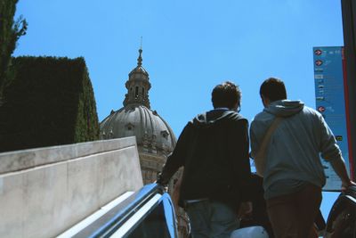 Rear view of people walking against clear sky