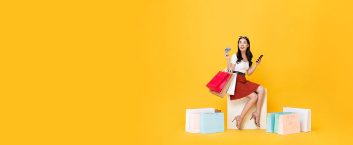 Woman with umbrella against yellow background