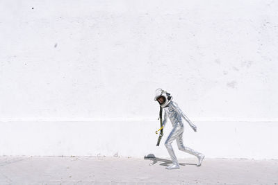 Side view of man standing against white wall