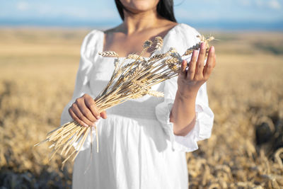 Midsection of woman holding camera while standing on field