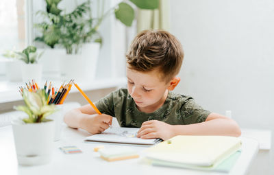 Boy drawing on book at home