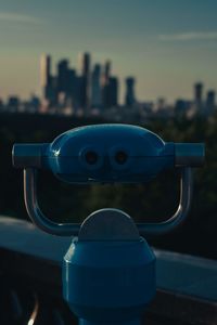 Close-up of coin-operated binoculars against cityscape