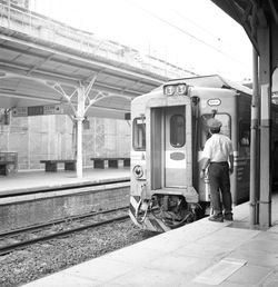 Rear view of train conductor standing by train at railroad station platform