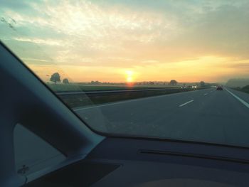 Cropped image of car on road at sunset