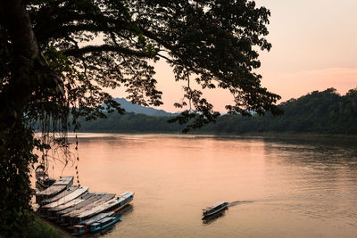 Boats moored in lake against sky during sunset