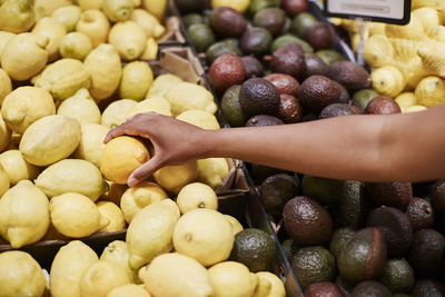 Hand choosing lemon in shop