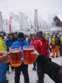 Close-up of hands toasting beer glasses