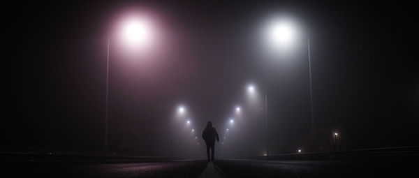 Walking on empty road along street lights at night