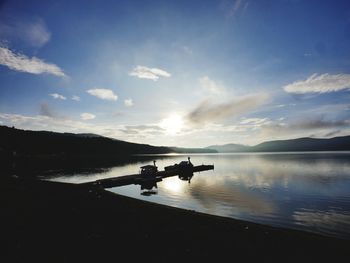 Silhouette boat in lake against sky during sunset