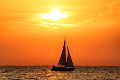 Sailboat sailing on sea against sky during sunset