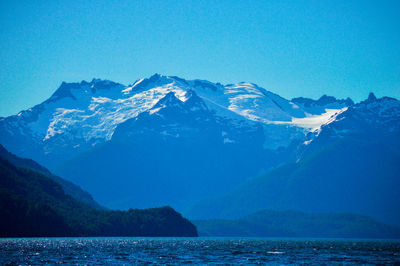 Scenic view of snowcapped mountains and sea against clear blue sky
