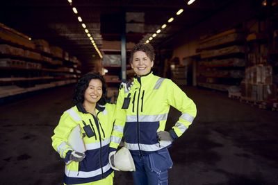 Portrait of smiling multiracial female coworkers in workwear standing in factory