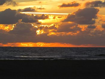 Scenic view of sea against cloudy sky during sunset