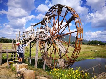 Boy standing by water wheel at farm