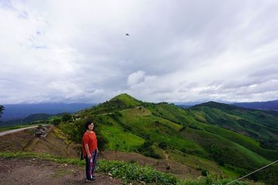 Rear view of man looking at mountains against sky