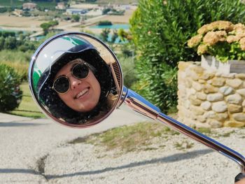 Low section of woman wearing sunglasses in a mirror of vespa scooter