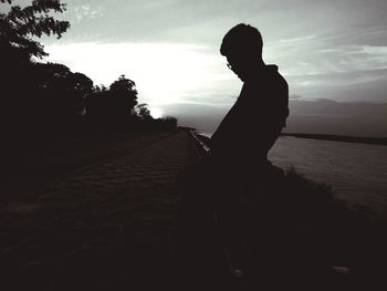 Silhouette woman sitting against sky during sunset