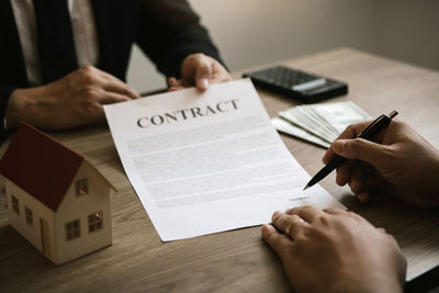 Midsection of man holding paper with text on table