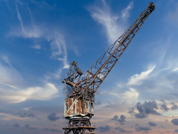 Low angle view of crane at construction site against sky