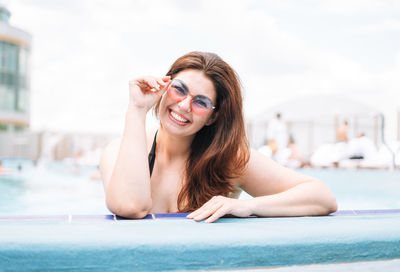 Stylish happy woman plus size in black swimsuit and sunglasses enjoying her life in pool