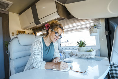 Side view of young woman using mobile phone while sitting at home