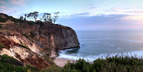 Scenic view of cliff by sea against sky