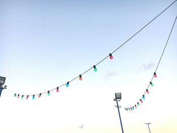 Low angle view of colorful light bulbs hanging against sky