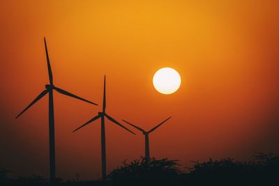 Silhouette windmills against sky during sunset