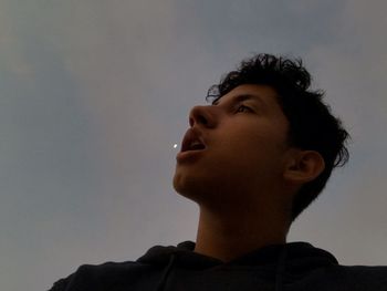 Portrait of a young man looking away against sky