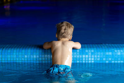 Shirtless man swimming in pool