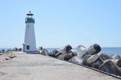 Lighthouse by sea against clear sky