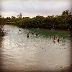 People floating on lake against sky