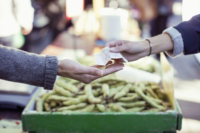 Cropped image of woman paying vegetable vendor