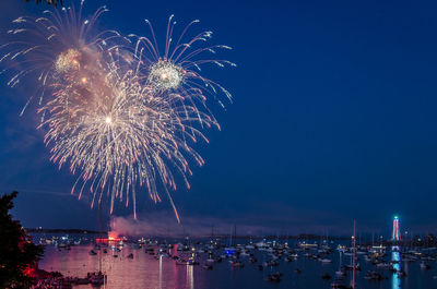 Firework display over sea against sky at night