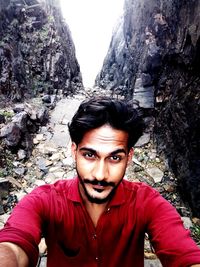 Portrait of young man on rock against trees