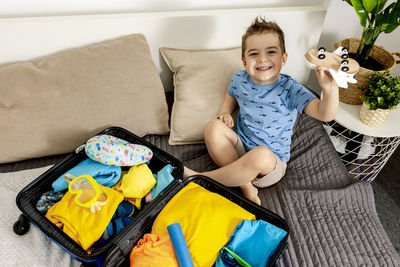 Little caucasian boy with blue shirt ready for vacation. happy child packs clothes