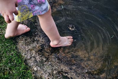Low section of boy standing in rippled pond