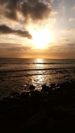 Scenic view of sea against cloudy sky at sunset