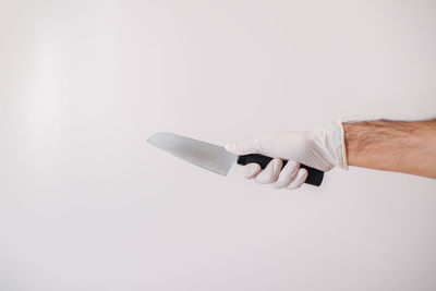 Close-up of hand holding paper over white background