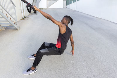 Young man practicing with suspension straps outdoors