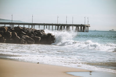 Waves splashing on shore against sky