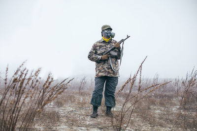 Full length of soldier with gun standing on field