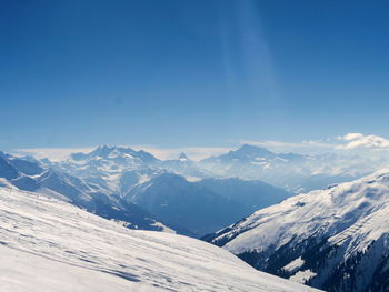 Scenic view of snowcapped mountains against blue sky